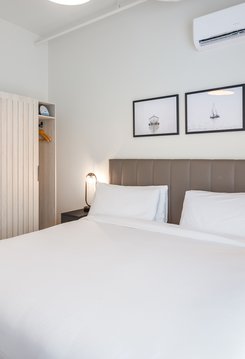 bedroom of two bedroom suite at steveston waterfront hotel with closet, side table and premium linen