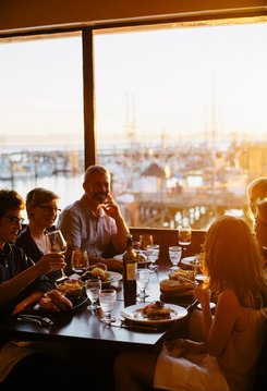 Diners in seafood restaurant, drinking wine, warm sunlight